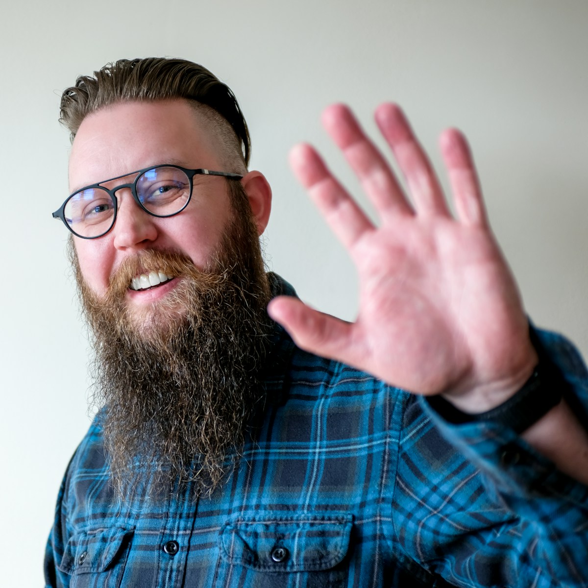 a man with a beard and glasses making a hand gesture